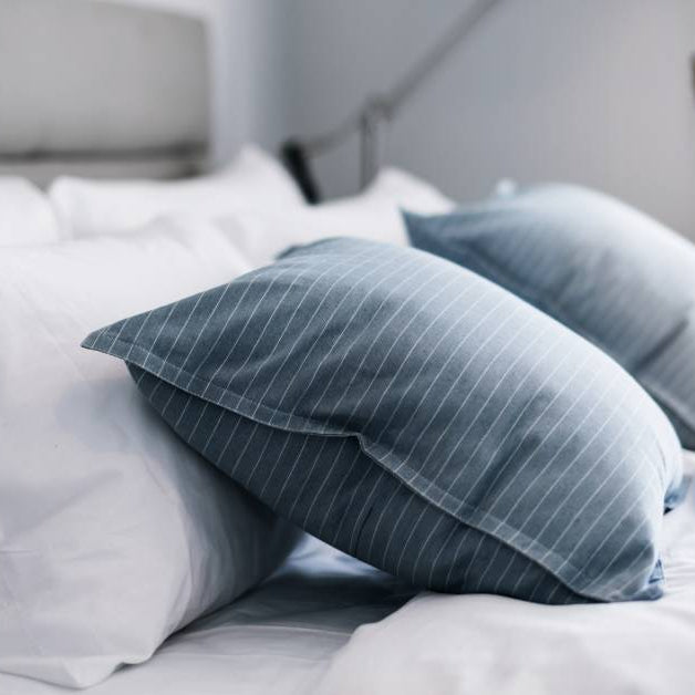 A bed that has been well made. There are six pillows on the bed and the comforter has been folded halfway down it. 