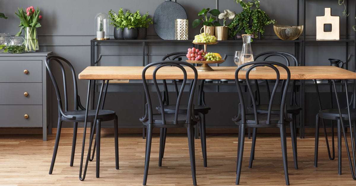 A dining room that has a table with a wooden top mixed with metal chairs. Most of the color scheme uses black.