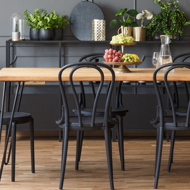 A dining room that has a table with a wooden top mixed with metal chairs. Most of the color scheme uses black.