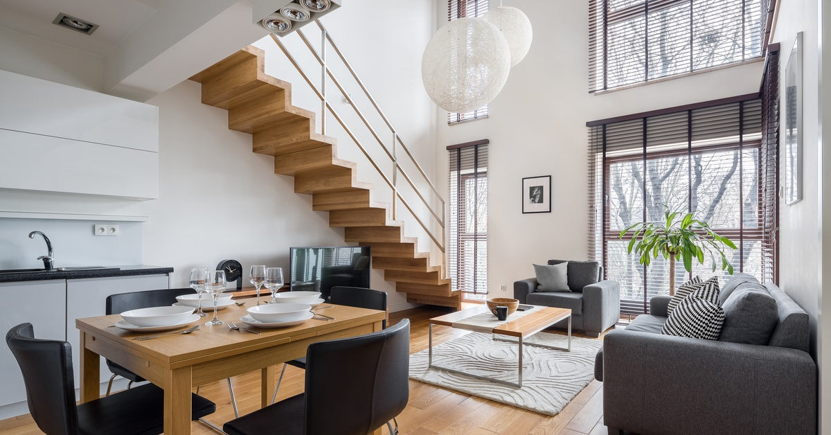 An open concept living room with a set of wooden stairs in the background. The furniture matches the room's style.