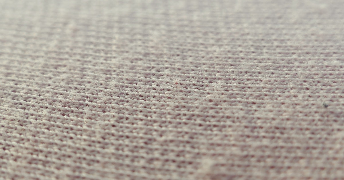 A very close view of some beige bed sheets. You can see the individual fibers and how they're weaved together.