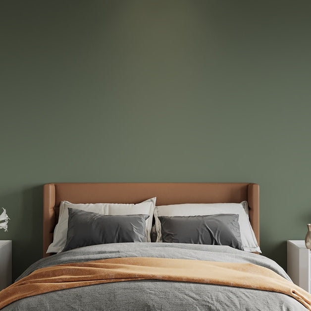 A bed and two nightstands set against a plain green wall. There is also a large indoor plant next to the bed.