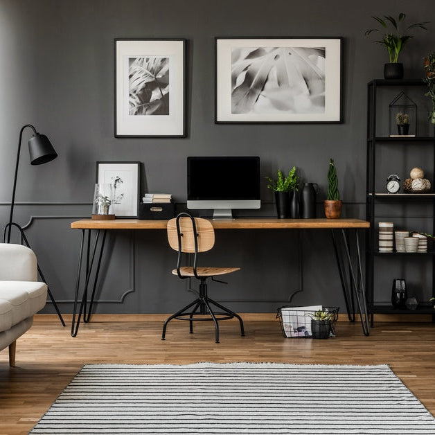 A home office that has a desk, chair, bookshelf, and lounge chair in it. All these items are spread throughout the room.
